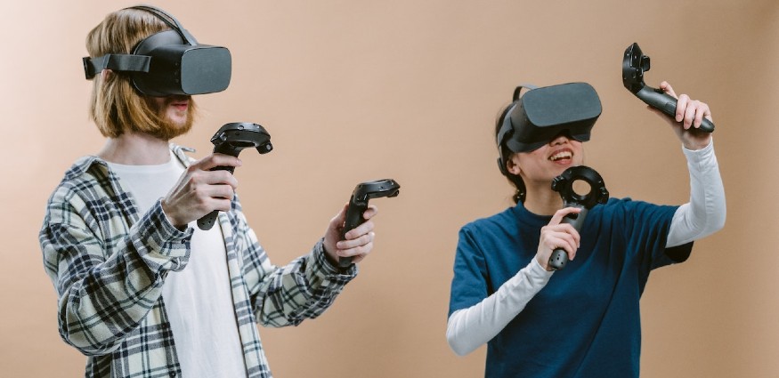 A man and a women playing a game whilst wearing virtual reality headsets.